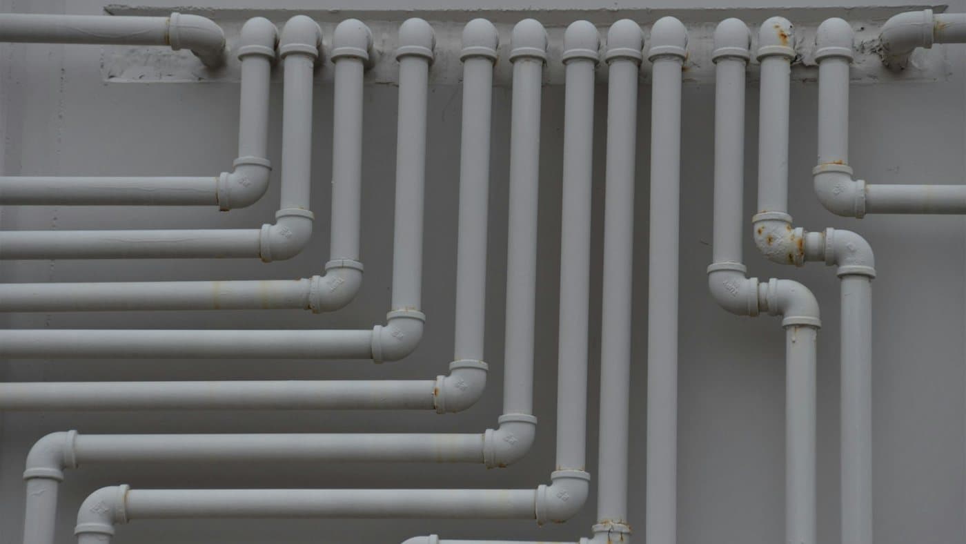 Verzweigtes weißes Rohrleitungsnetz mit zahlreichen Abgängen an einer Wand